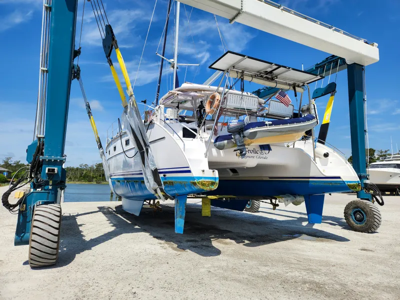 Slide: The Image of Antares 44i catamaran from 2014 being lifted by a boat hoist near the water. - 2
