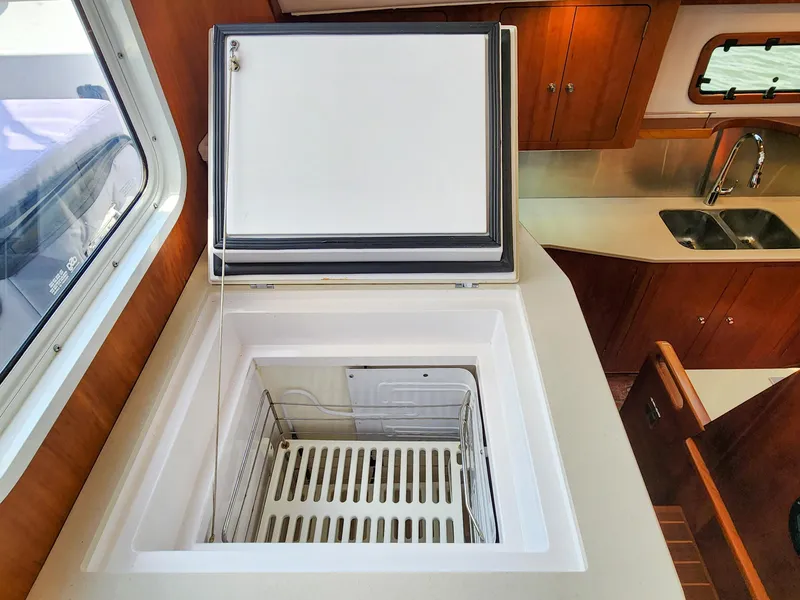 Slide: The Image of Open freezer in 2014 Antares 44i yacht kitchen with wooden cabinets and stainless steel sink. - 21