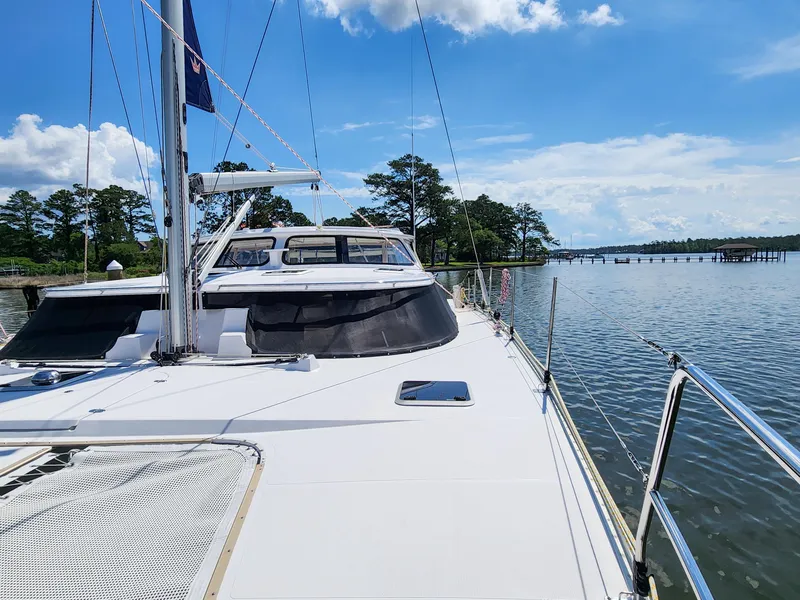 Slide: The Image of Sailing yacht Antares 44i, 2014 model, docked by a scenic waterfront under a clear blue sky. - 34