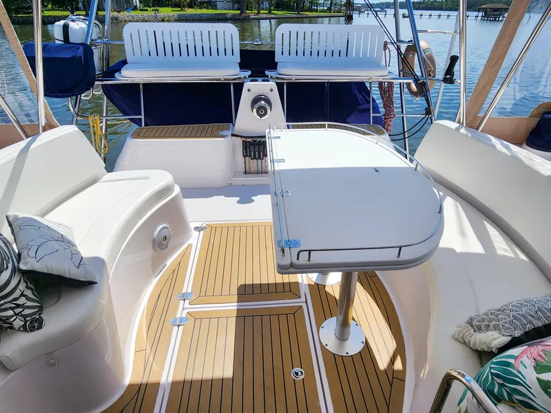 Slide: The Image of 2014 Antares 44i yacht cockpit with seating, table, and teak flooring on a sunny day. - 46