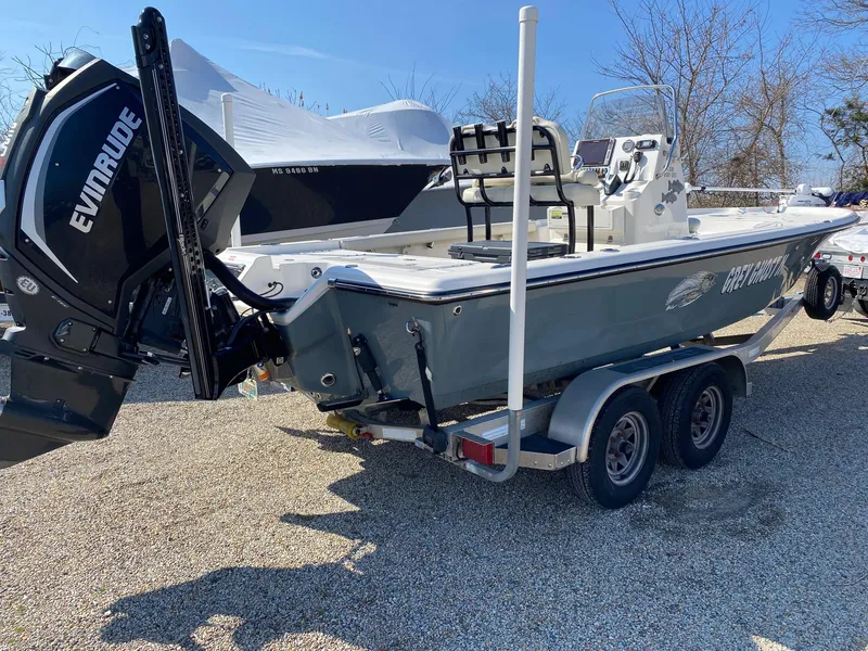 Slide: The Image of 2020 Key West 230 Bay Reef boat on trailer with Evinrude engine, parked outdoors. - 2