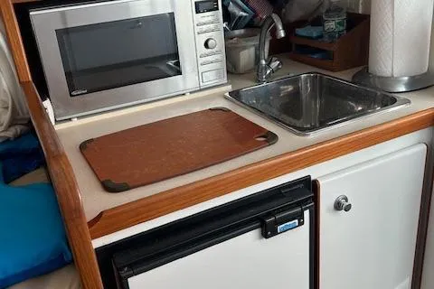 Slide: The Image of 2004 Tiara Yachts 2900 Coronet kitchenette with microwave, sink, and cutting board. - 5