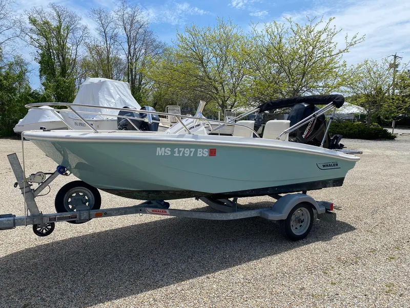 Slide: The Image of 2022 Boston Whaler 130 Super Sport boat on trailer, parked outdoors. - 1