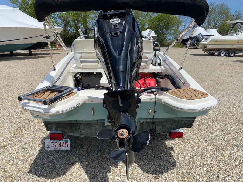 Slide: The Image of 2022 Boston Whaler 130 Super Sport boat, rear view with outboard motor, parked on gravel. - 2