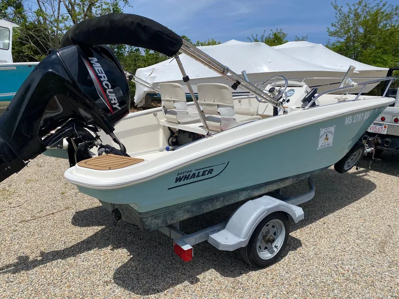 Slide: The Image of 2022 Boston Whaler 130 Super Sport boat on trailer, featuring a Mercury engine. - 4
