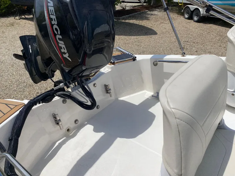 Slide: The Image of 2022 Boston Whaler 130 Super Sport boat interior with Mercury engine, white seating, and clean deck. - 8