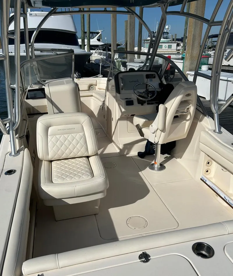 Slide: The Image of 2018 Grady-White Freedom 235 boat interior with helm and seating at marina. - 25