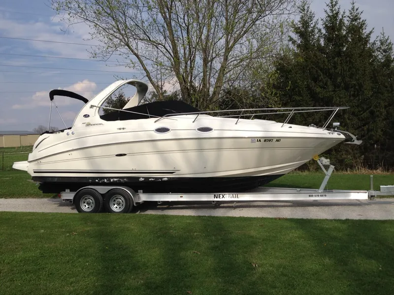 Slide: The Image of 2003 Sea Ray 280 Sundancer boat on trailer, parked on grass with trees in background. - 0