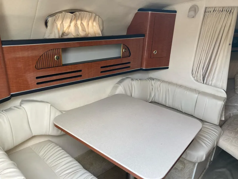 Slide: The Image of Interior of 2003 Sea Ray 280 Sundancer with white seating and wooden cabinetry. - 5