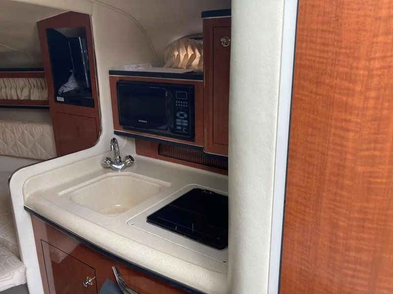 Slide: The Image of 2003 Sea Ray 280 Sundancer interior kitchen with sink, stove, and microwave. - 6