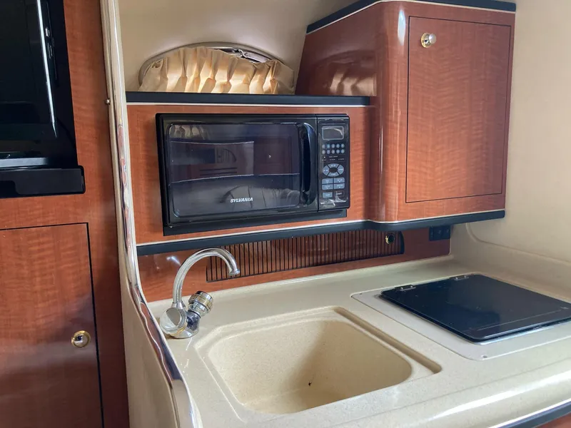 Slide: The Image of 2003 Sea Ray 280 Sundancer galley with microwave, sink, and stove. - 9
