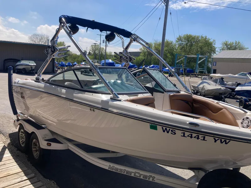 Slide: The Image of 2008 MasterCraft MariStar 215 boat on trailer, parked outdoors under clear sky. - 1