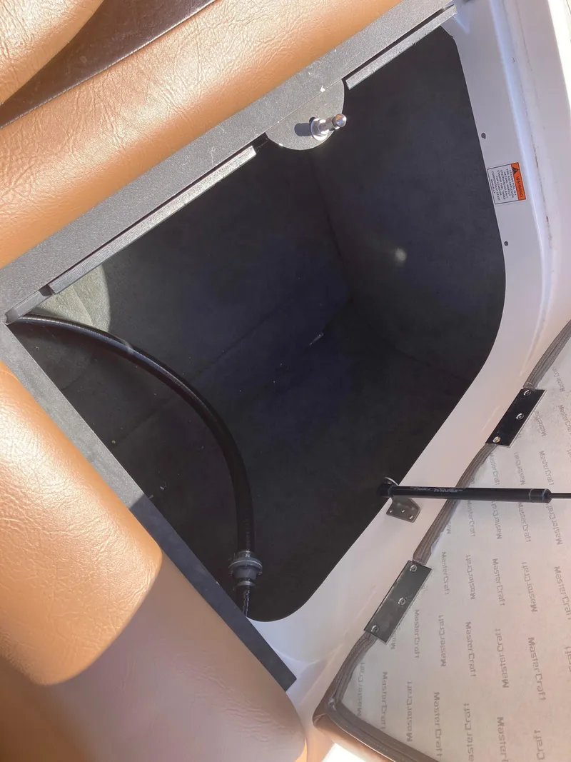 Slide: The Image of Storage compartment in a 2008 MasterCraft MariStar 215 boat, featuring brown upholstery. - 10