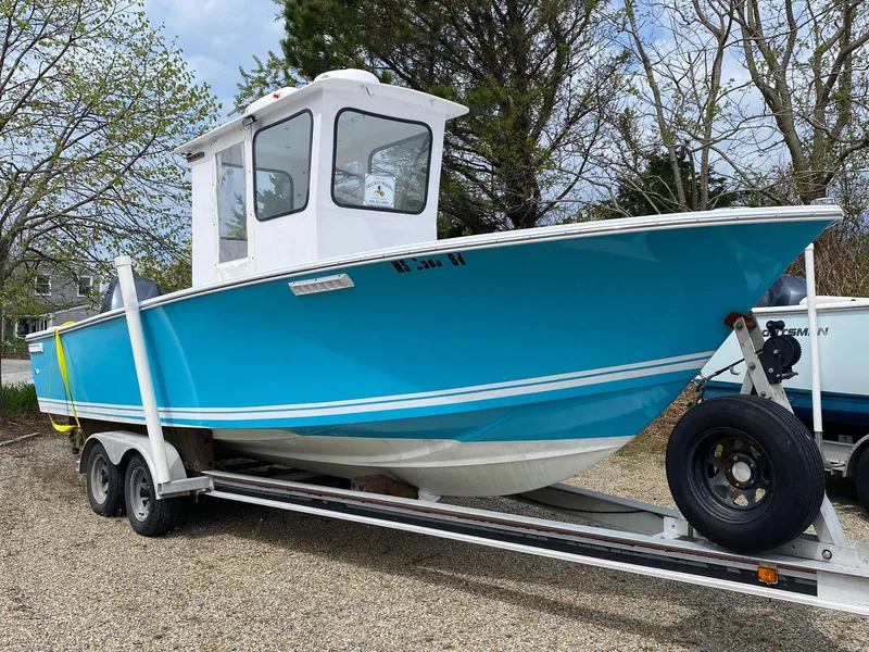 Slide: The Image of 1987 SeaCraft 23 CC boat on trailer, vibrant blue hull, parked outdoors. - 2