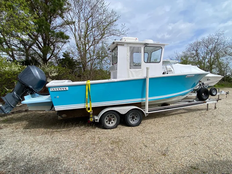 Slide: The Image of 1987 SeaCraft 23 CC boat on trailer, blue hull, parked outdoors. - 3