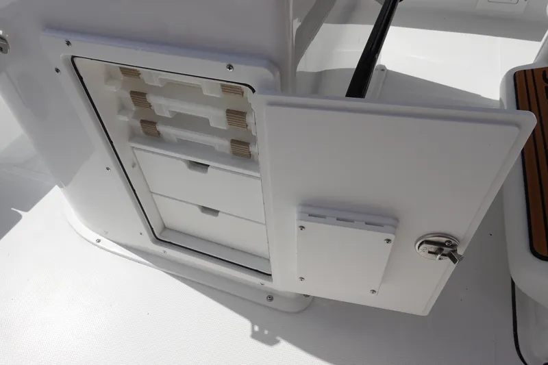 Slide: The Image of 2026 Sea Hunt BX 25 FS boat storage compartment with open door and drawers. - 23