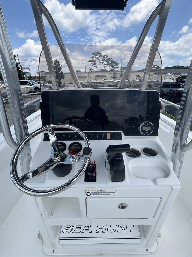 Slide: The Image of 2018 Sea Hunt Triton 210 boat console with steering wheel and controls under blue sky. - 13