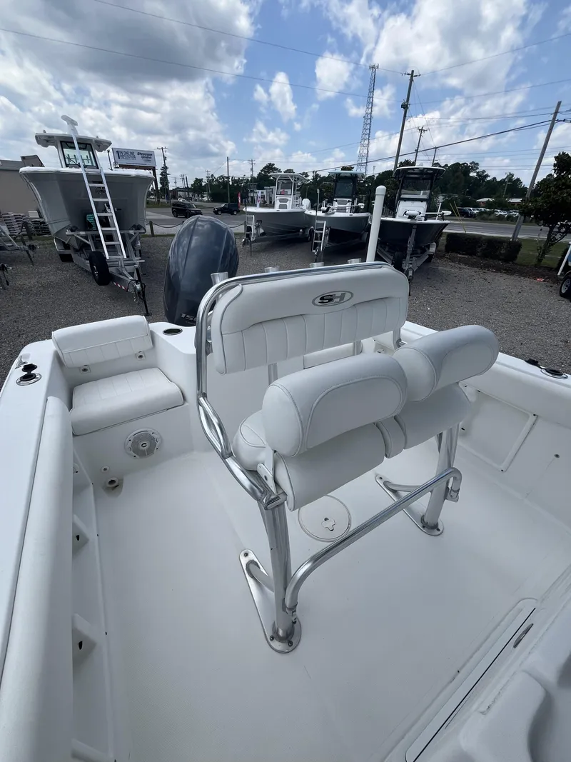 Slide: The Image of 2018 Sea Hunt Triton 210 boat interior with seating and console, under a partly cloudy sky. - 16