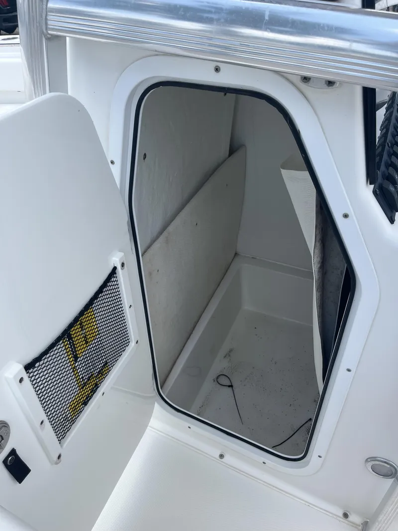 Slide: The Image of 2018 Sea Hunt Triton 210 boat storage compartment with open door and netted pocket. - 18