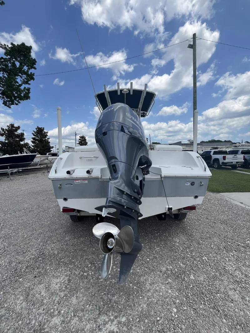 Slide: The Image of 2018 Sea Hunt Triton 210 boat with outboard motor, parked on gravel under a cloudy sky. - 3