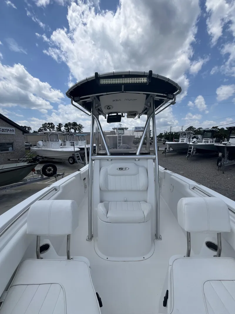 Slide: The Image of 2018 Sea Hunt Triton 210 boat with T-top, docked under a partly cloudy sky. - 9