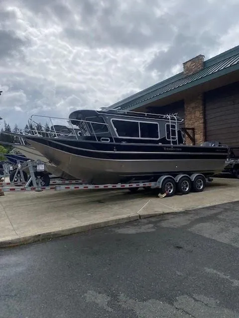 Slide: The Image of 2024 Spartan 2800 Olympia boat on trailer, parked outside a building under cloudy skies. - 0