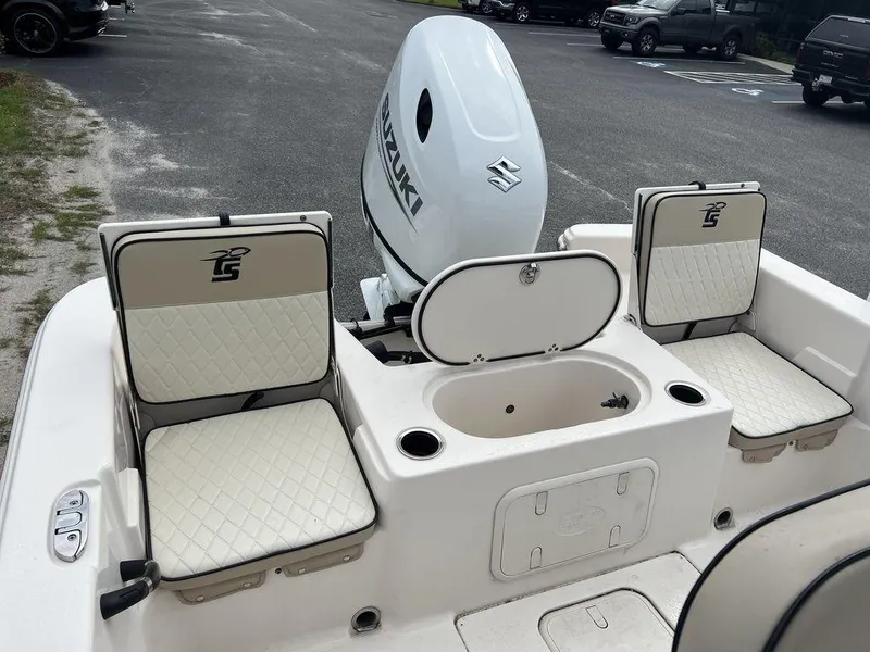 Slide: The Image of 2023 Carolina Skiff 21 LS boat interior with Suzuki engine, featuring cushioned seating and storage. - 16