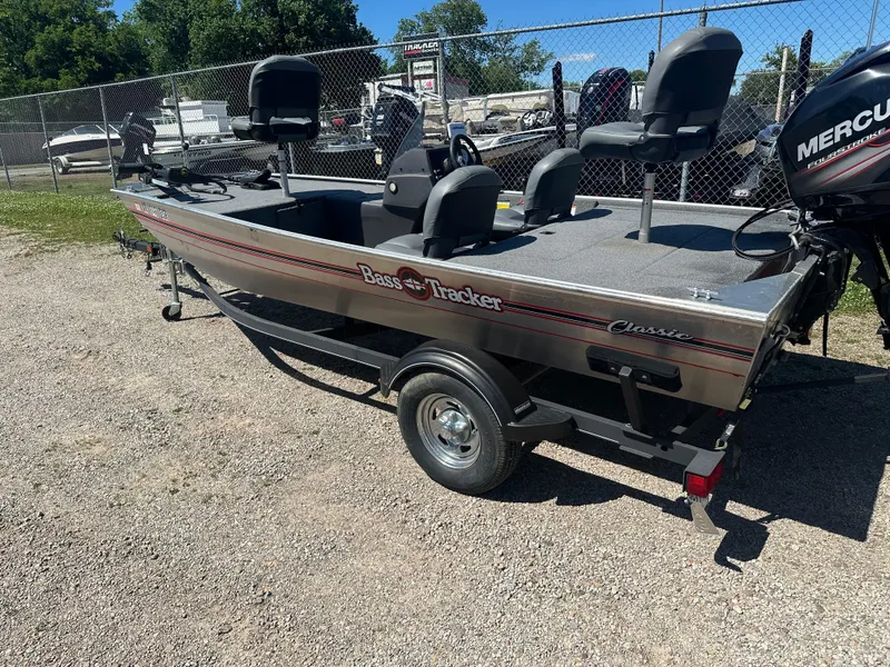 Slide: The Image of 2019 Tracker Classic boat with Mercury engine, parked on gravel near a fence. - 4