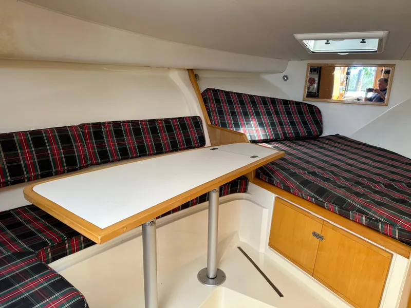 Slide: The Image of 1994 Bertram 30 Express Fisherman cabin with plaid seating, table, and wooden storage. - 10