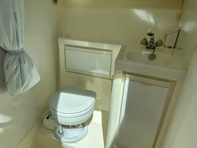 Slide: The Image of 1994 Bertram 30 Express Fisherman boat bathroom with toilet, sink, and storage cabinet. - 14