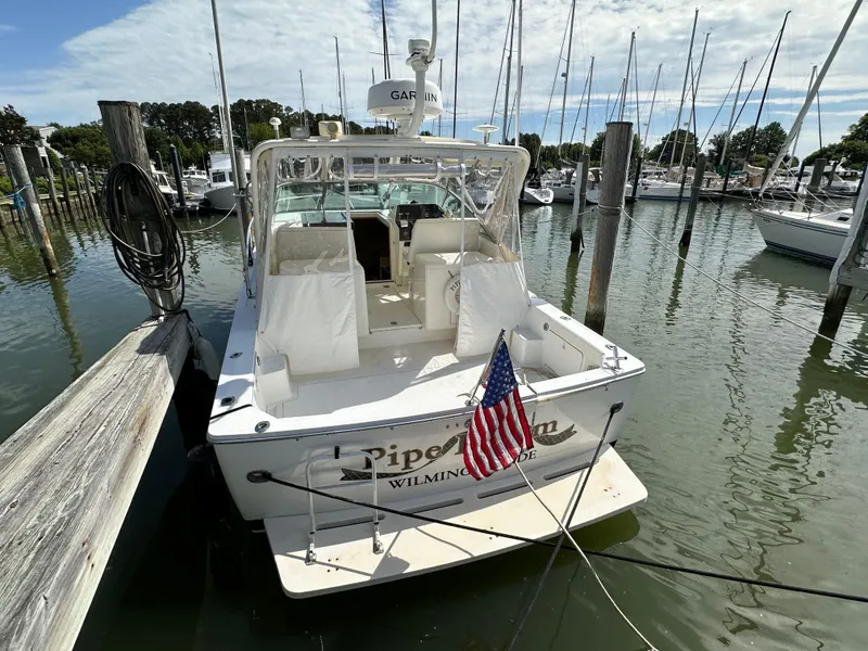 Slide: The Image of 1994 Bertram 30 Express Fisherman docked, displaying American flag, in marina setting. - 15