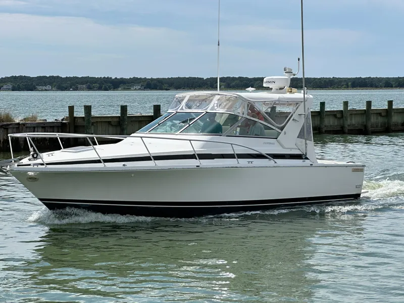 Slide: The Image of 1994 Bertram 30 Express Fisherman cruising on calm waters near a wooden dock. - 18