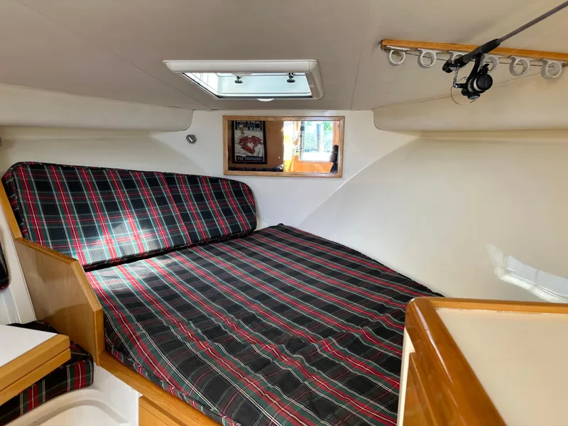 Slide: The Image of 1994 Bertram 30 Express Fisherman cabin with plaid bedding and natural light. - 8