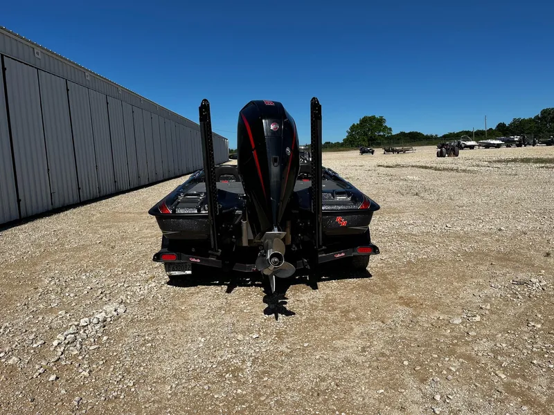 Slide: The Image of 2020 Bass Cat Lynx boat, rear view, parked on gravel near a large building. - 7