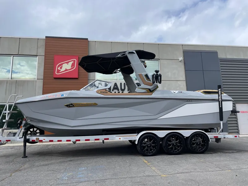 Slide: The Image of 2024 Nautique Super Air Nautique G25 Paragon boat on trailer, parked outside a building. - 1