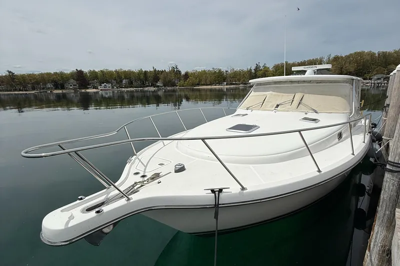 Slide: The Image of 2002 Pursuit 3800 Express boat docked on calm water, surrounded by trees. - 12
