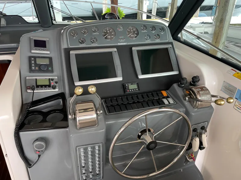 Slide: The Image of Control panel of a 2002 Pursuit 3800 Express boat with dual screens and steering wheel. - 27