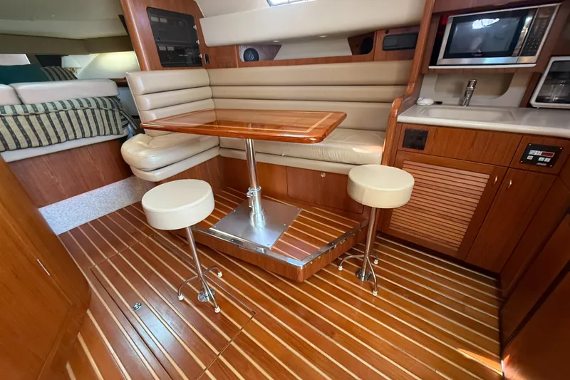 Slide: The Image of 2002 Pursuit 3800 Express yacht interior with wooden flooring, dining area, and kitchenette. - 41