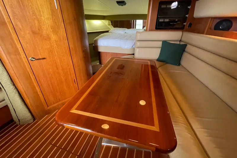 Slide: The Image of Interior of 2002 Pursuit 3800 Express yacht with wooden table and beige seating. - 44
