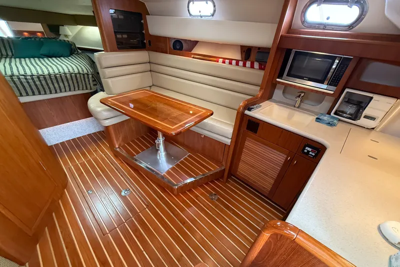 Slide: The Image of 2002 Pursuit 3800 Express yacht interior with wood flooring, dining area, and kitchenette. - 52