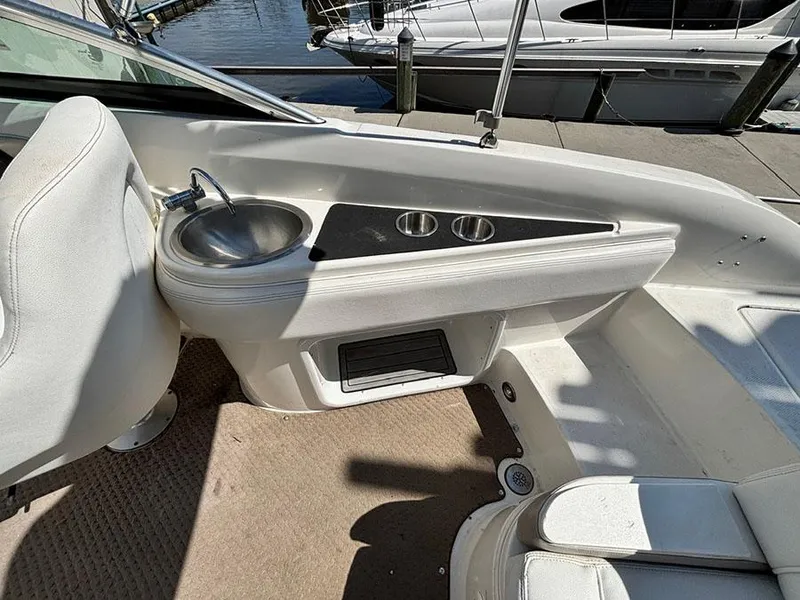 Slide: The Image of 2013 Sea Ray 240 Sundeck interior with sink and cup holders, docked at marina. - 8