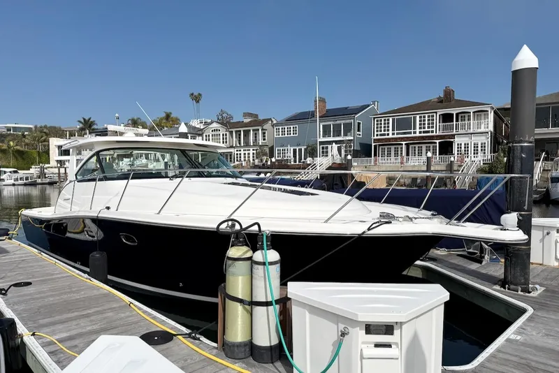 Slide: The Image of 2020 Tiara Yachts 3900 Open "Coronet" docked at a marina with waterfront homes. - 0