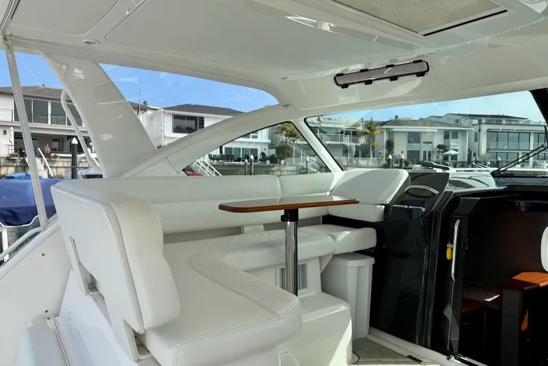 Slide: The Image of 2020 Tiara Yachts 3900 Open "Coronet" interior with white seating and wooden table. - 12