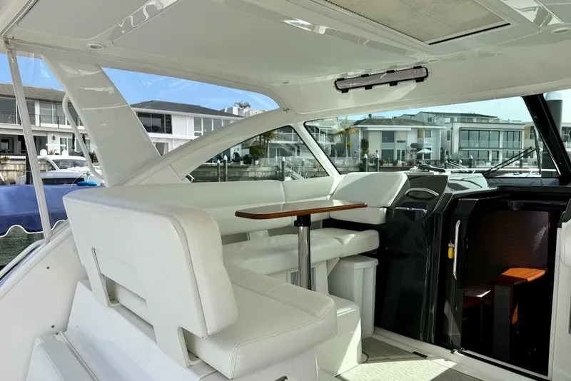 Slide: The Image of 2020 Tiara Yachts 3900 Open "Coronet" interior with white seating and wooden table. - 13