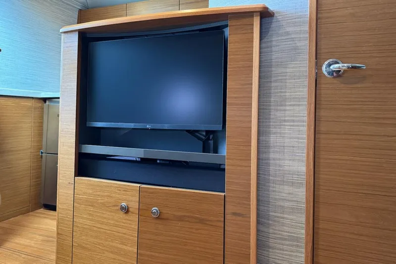 Slide: The Image of 2020 Tiara Yachts 3900 Open "Coronet" interior with built-in TV and wooden cabinetry. - 30