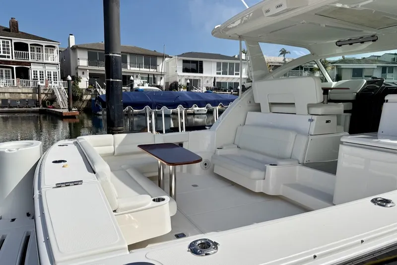 Slide: The Image of 2020 Tiara Yachts 3900 Open "Coronet" with elegant seating, docked near waterfront homes. - 6
