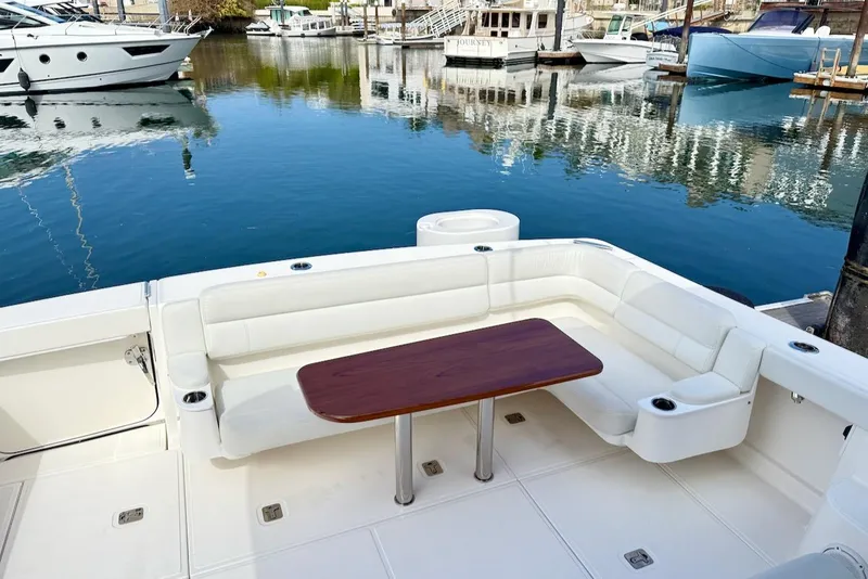 Slide: The Image of 2020 Tiara Yachts 3900 Open "Coronet" with white seating and wooden table in marina. - 7