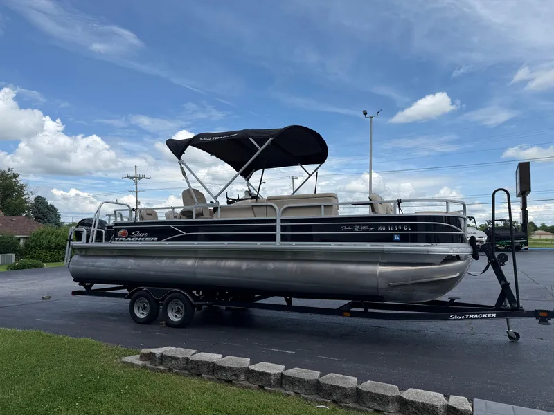 Slide: The Image of 2019 Sun Tracker Fishin' Barge 24 DLX pontoon boat on trailer, parked outdoors. - 3