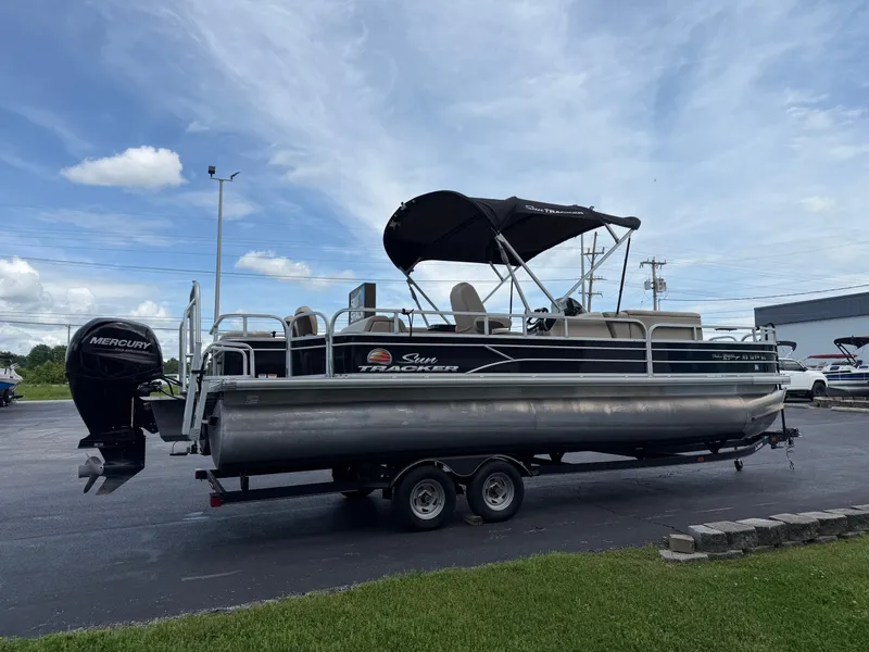 Slide: The Image of 2019 Sun Tracker Fishin' Barge 24 DLX pontoon boat on trailer, parked outdoors. - 4