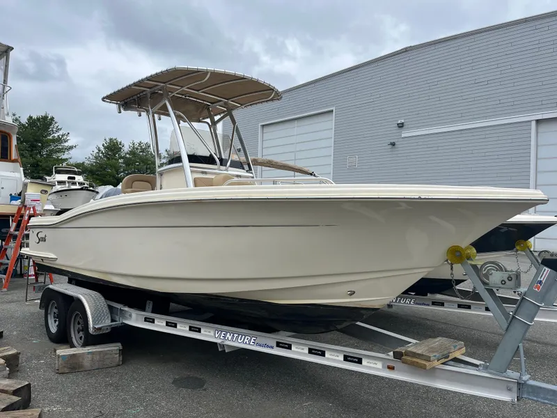 Slide: The Image of 2020 Scout 215 XSF boat on trailer, parked outdoors near a building. - 1